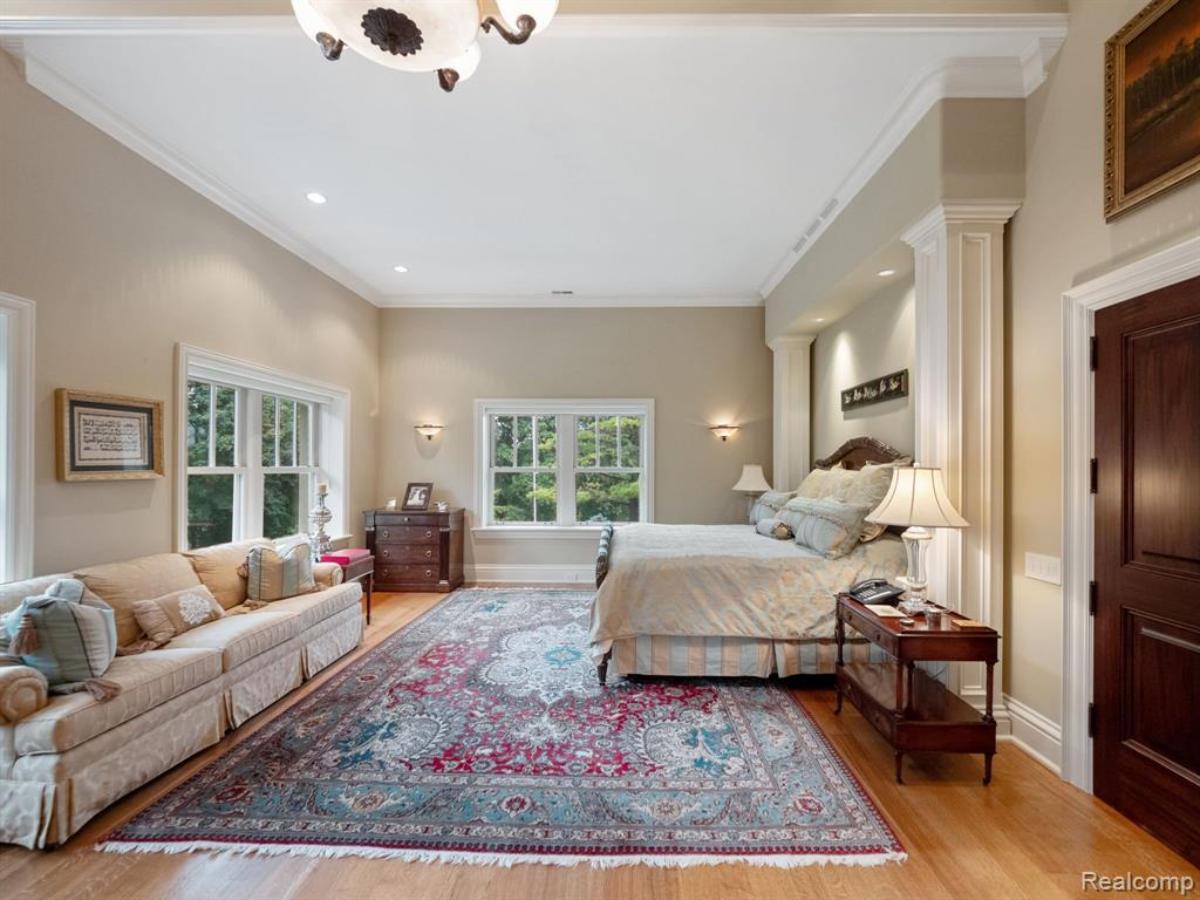 Bedroom with a large bed, glass windows and a wooden floor.