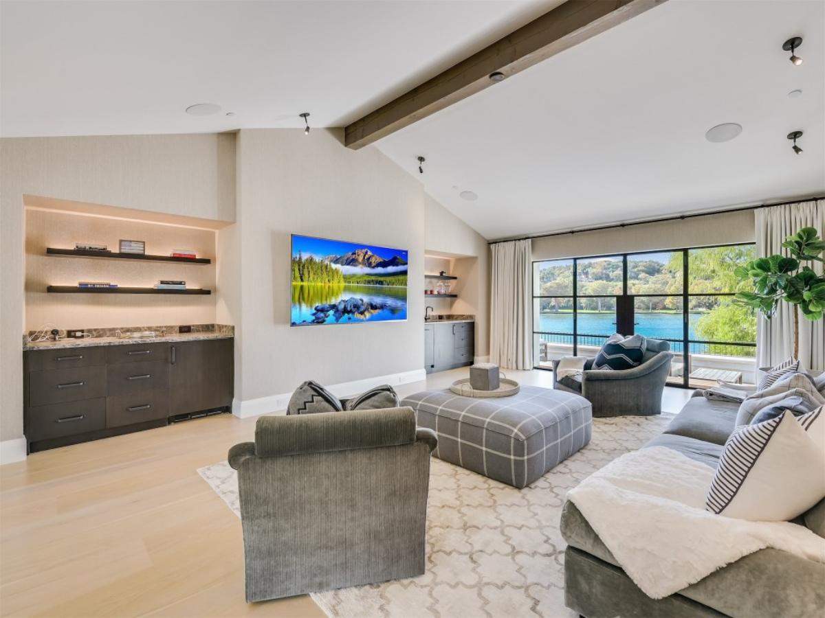 Living room with couches, glass windows, TV and a large rug.