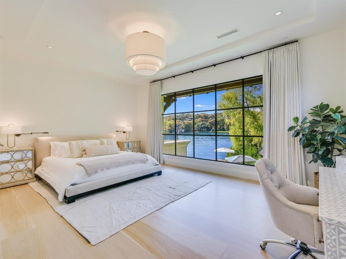 Bedroom with a large bed, glass windows and large rug.