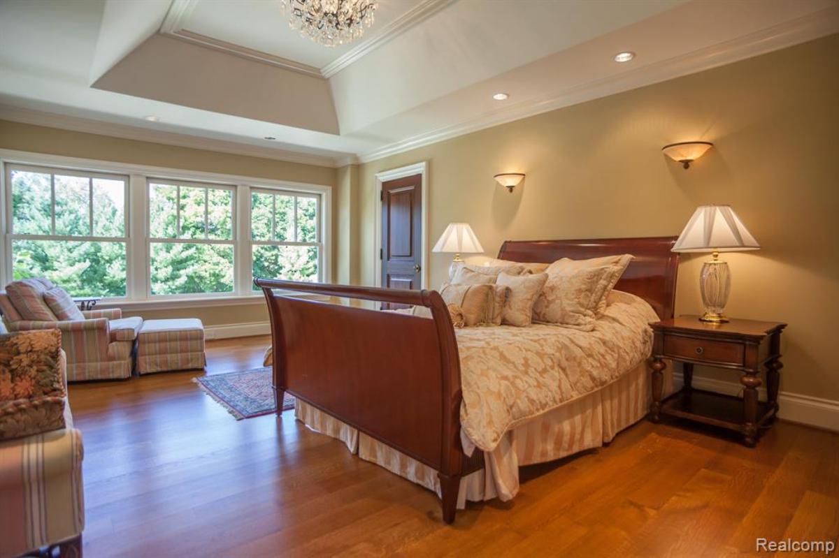 Bedroom with a large bed, glass windows and a wooden floor.