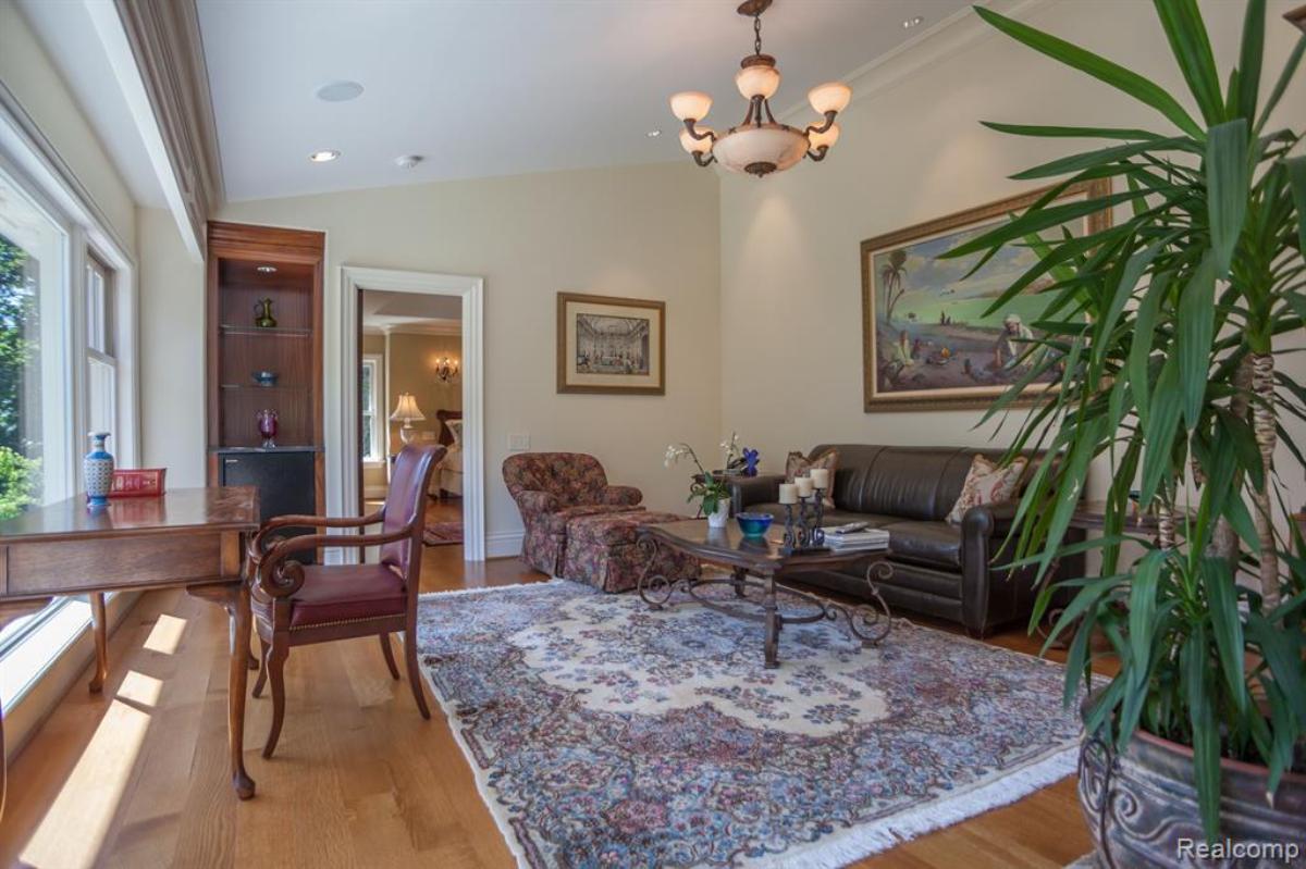 Sitting room with a couch, glass windows, chandelier and wooden floor.