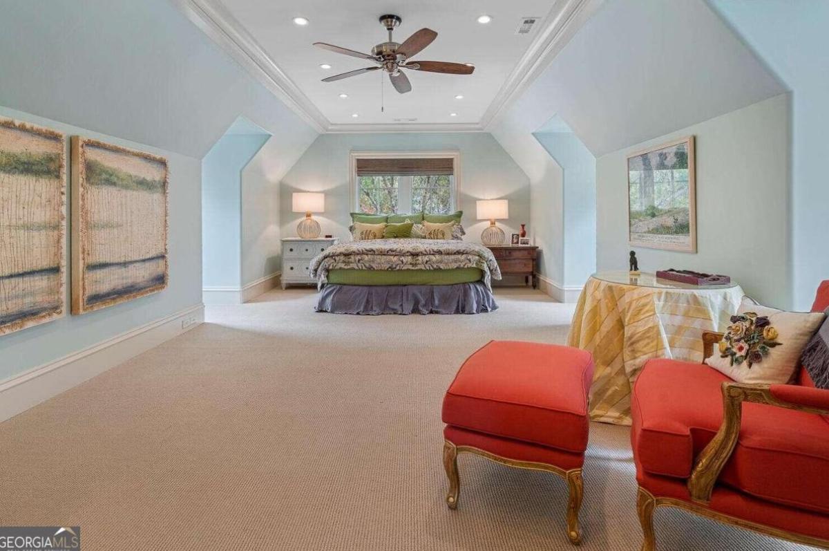 Bedroom with a large bed, carpet flooring and glass windows.