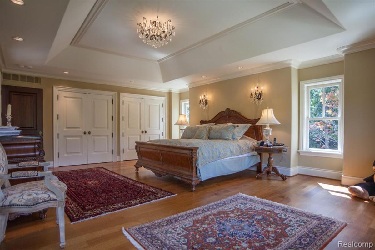 Bedroom with a large bed, chandelier and glass windows.