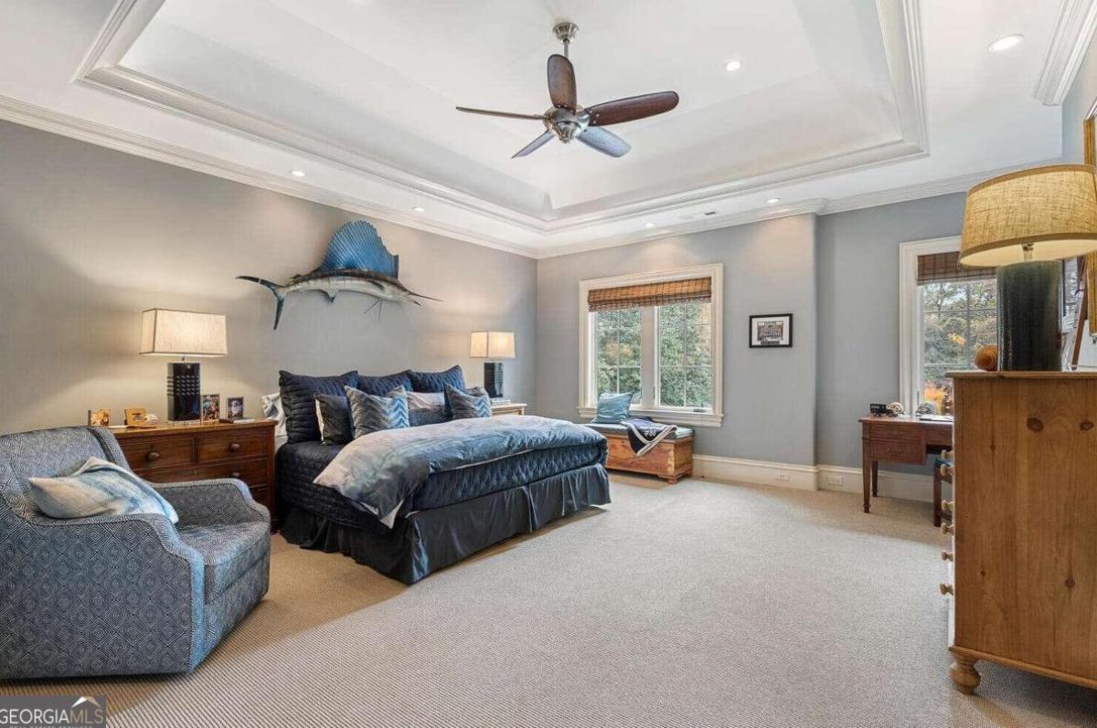 Bedroom with a large bed, carpet flooring and glass windows.