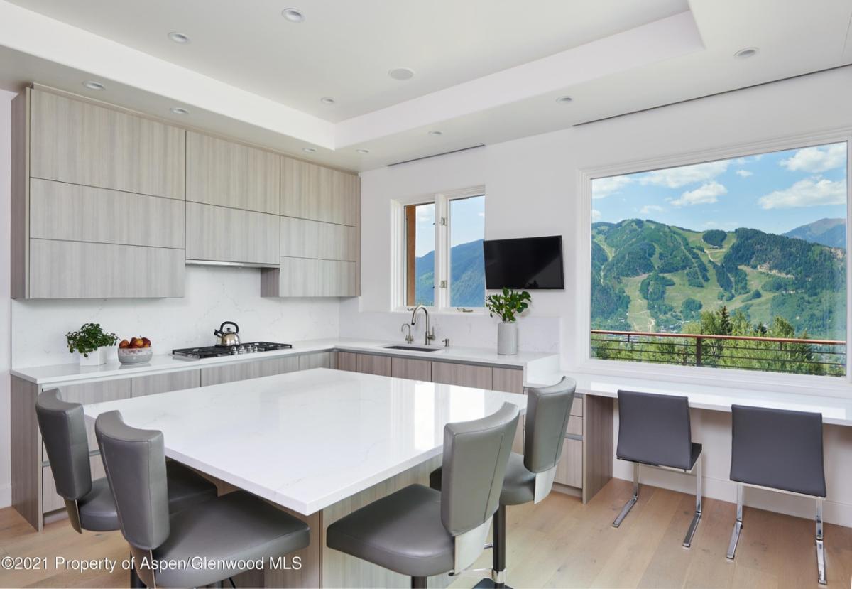 Kitchen with a table, chairs and a large window overlooking the mountains.