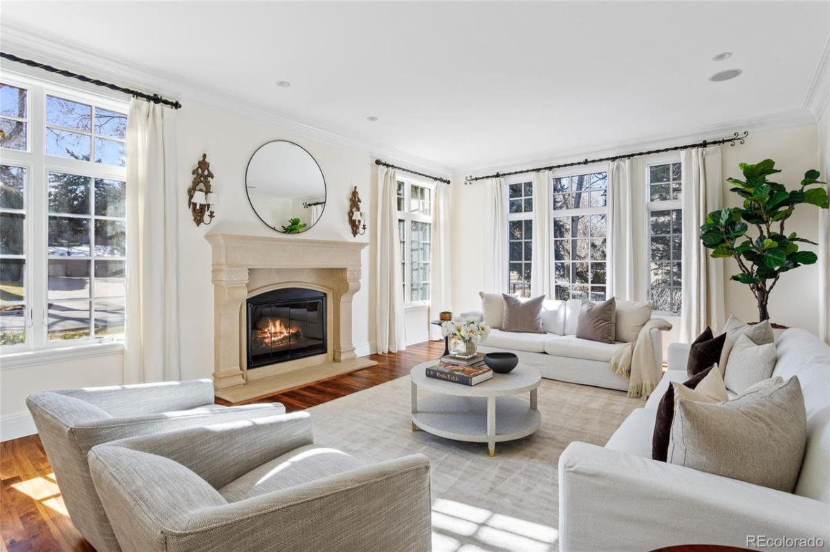 Living room with couches, glass windows, fireplace and a large rug.