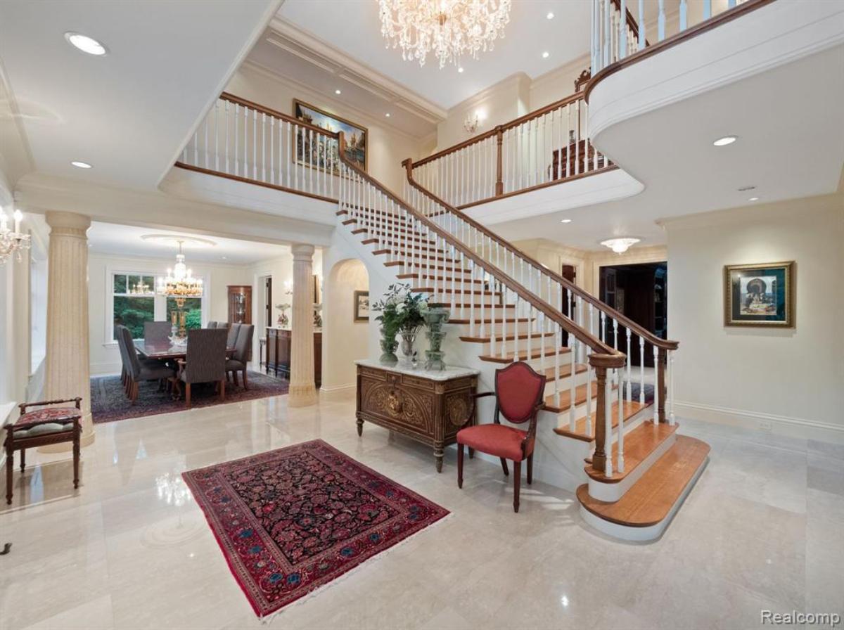 Foyer with a staircase, large rug and a chandelier.