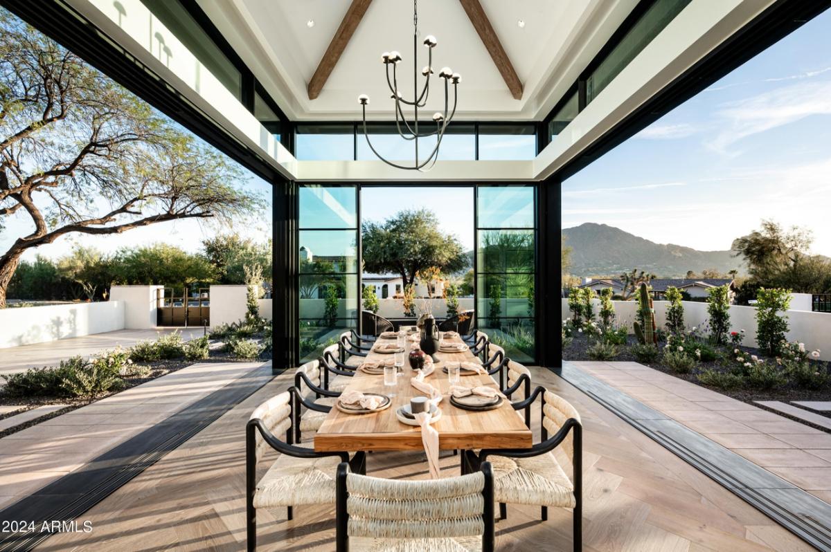 Dining room with a large table, chairs and chandelier.