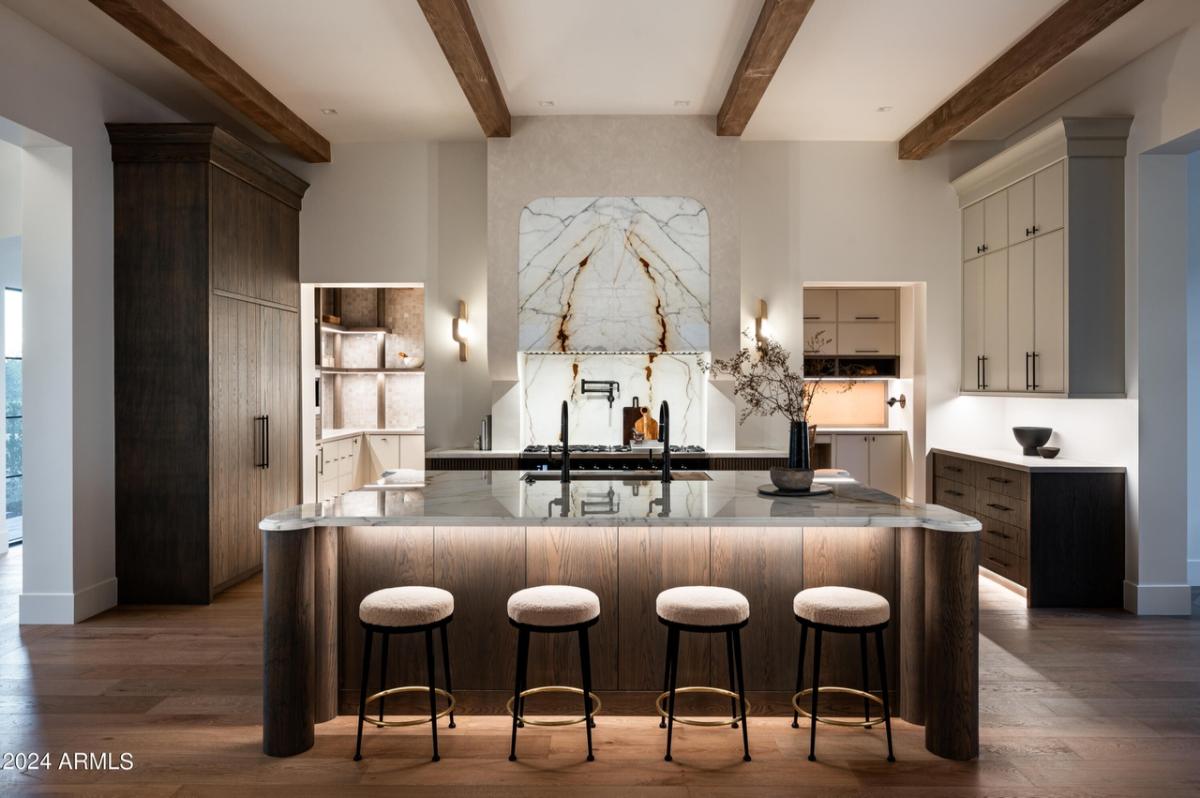 Kitchen with a large island, chairs and wood flooring.