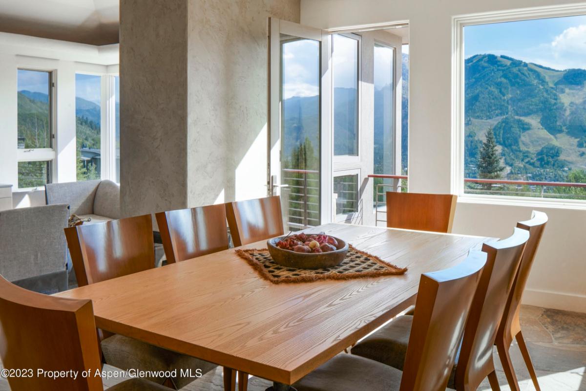 Dining room with a large wooden table, chairs and glass door.