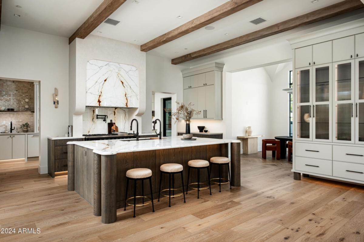 Kitchen with a large island, chairs and wood flooring.
