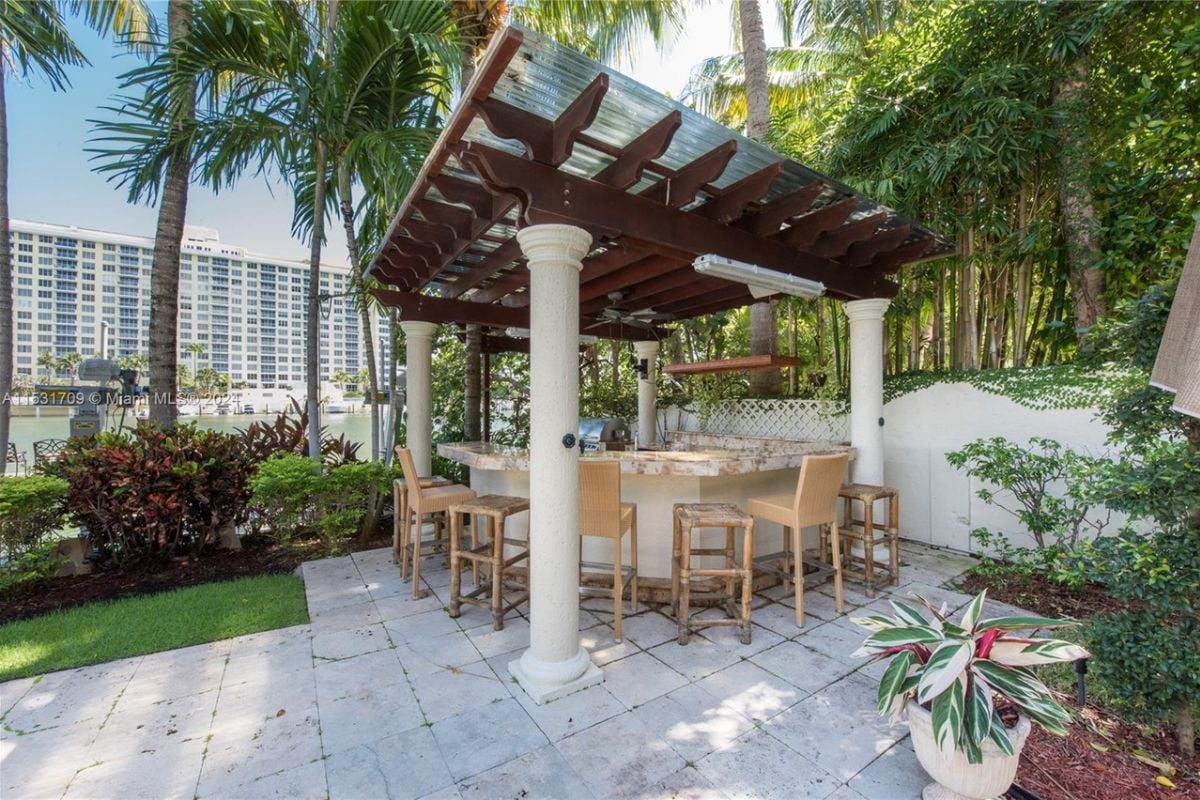 A kitchen with chairs under a pergola.