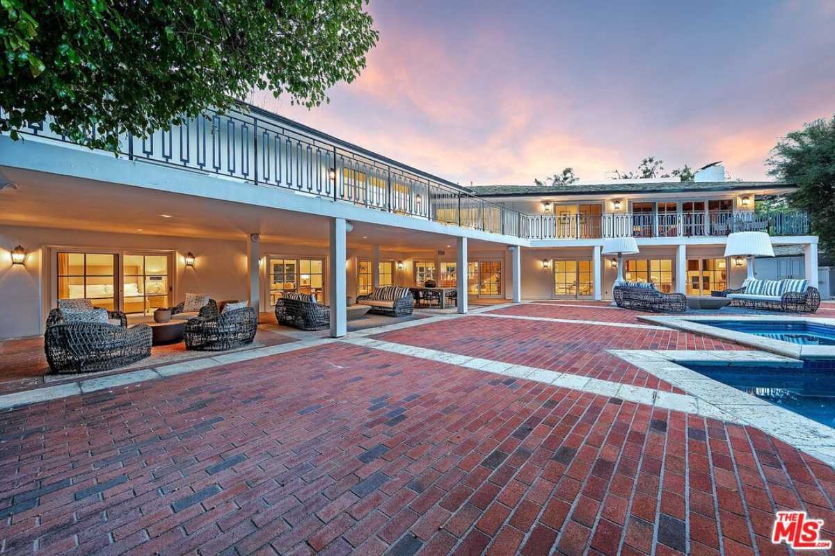 A brick courtyard featuring a pool and chairs.