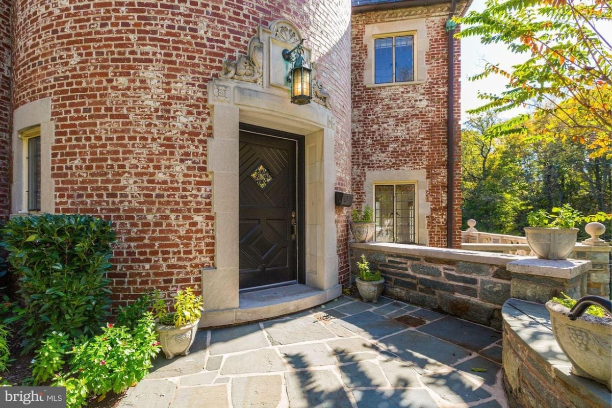 A front entry with a wooden door and a lamp on top.