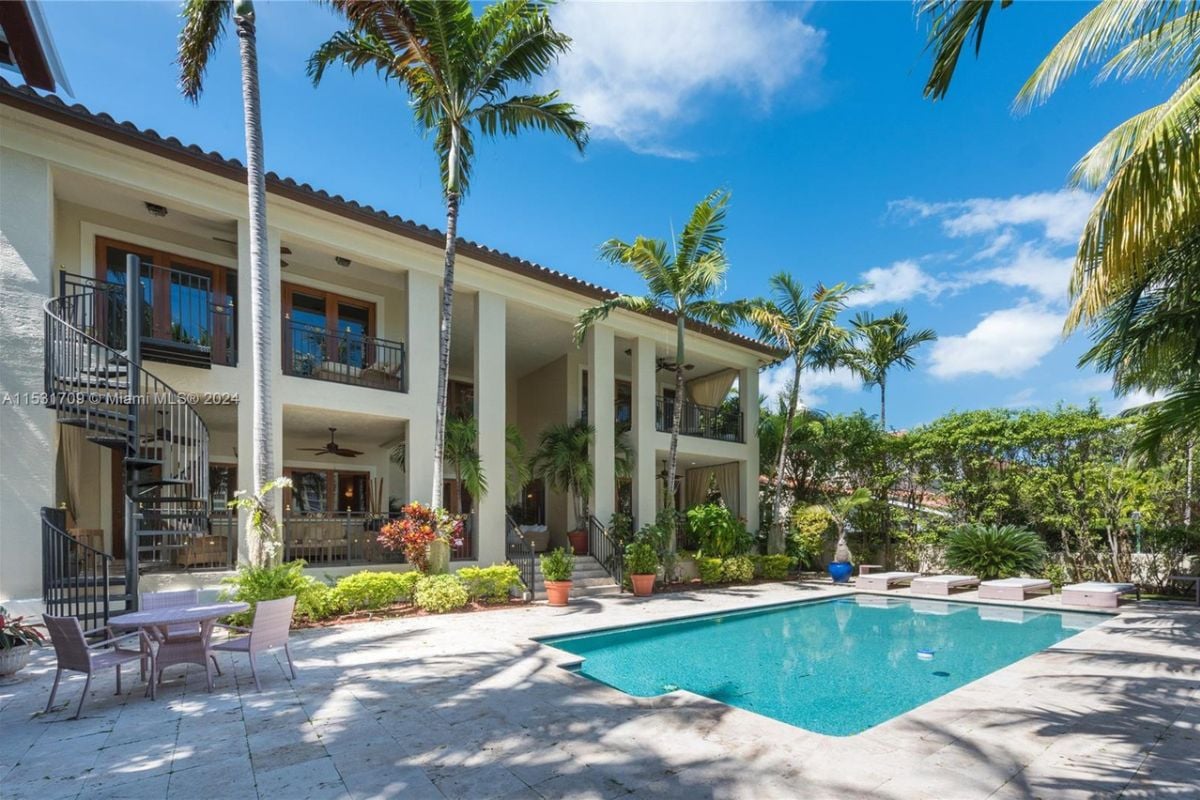A swimming pool nestled among trees and plants, complete with chairs and a coffee table.