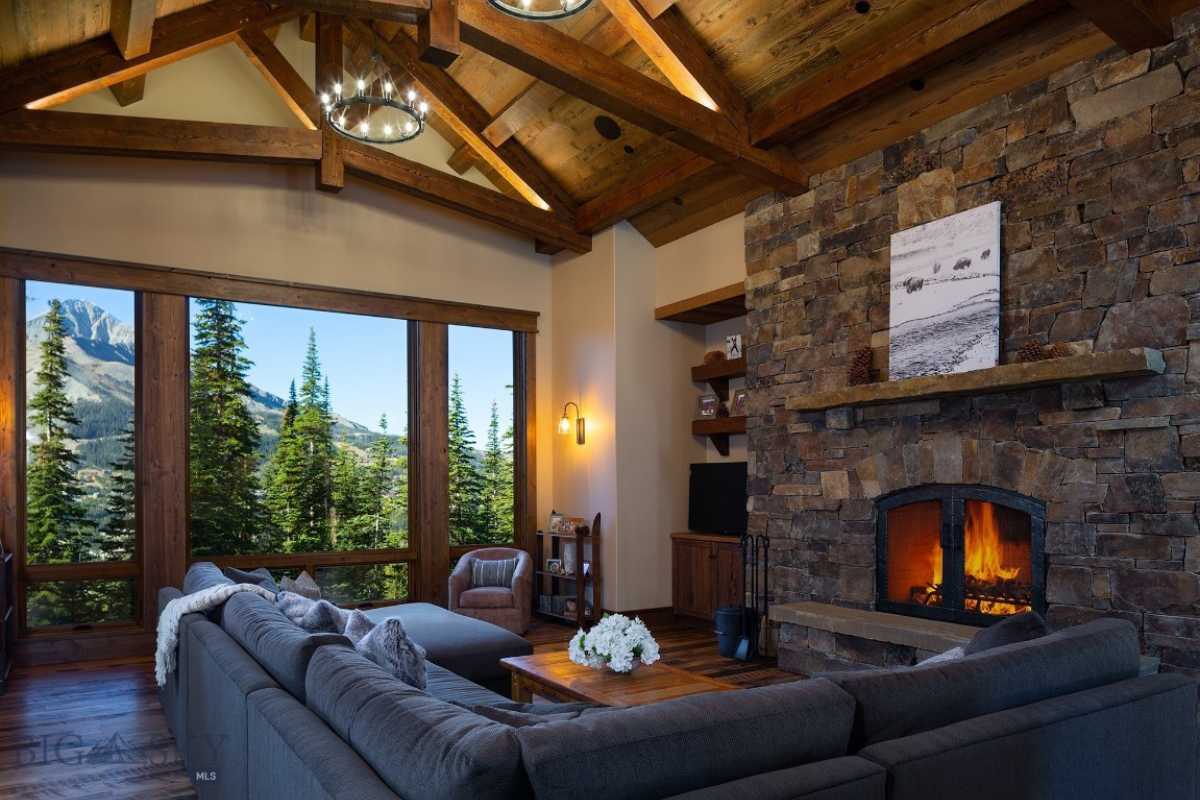 A living room with a fireplace, exposed beam ceiling, wooden floor, couch, and center table.