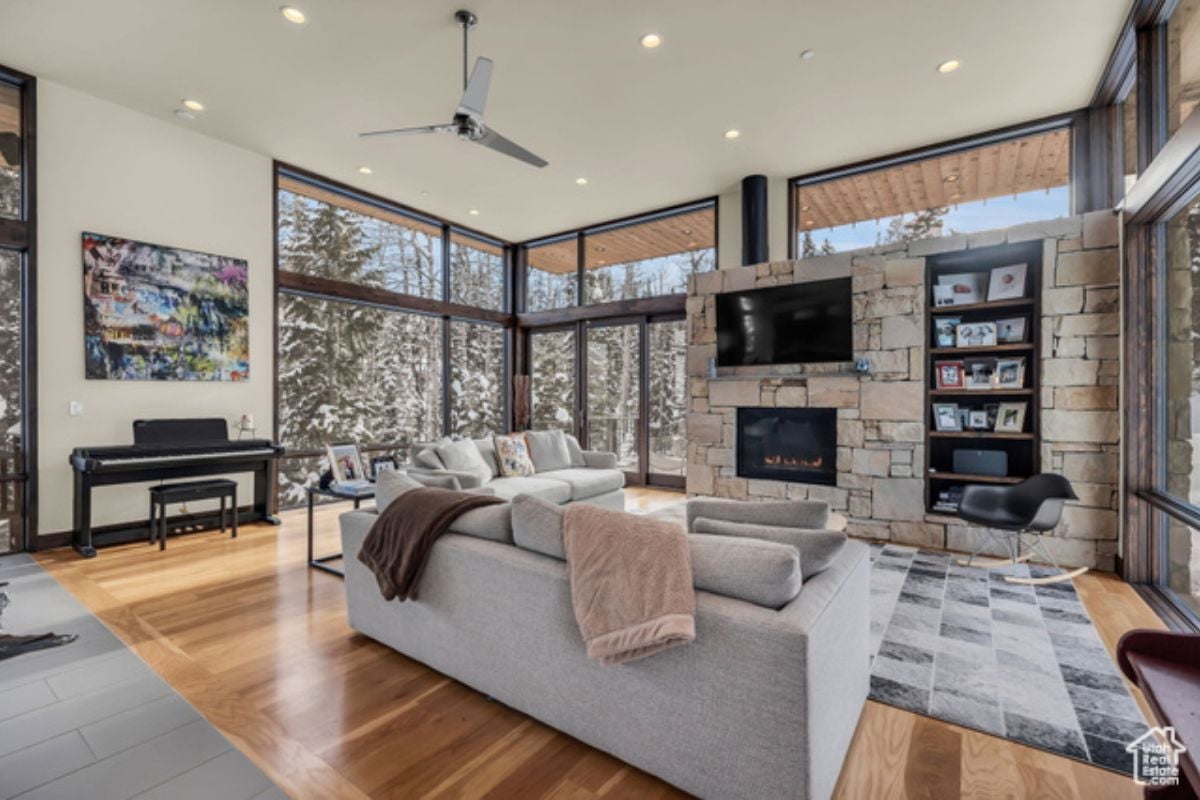 A living room with a couch, TV, rug, wooden floor, and white ceiling fan.