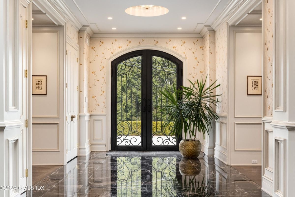 A foyer with a potted plant, tiled floor, white walls, and a white ceiling.