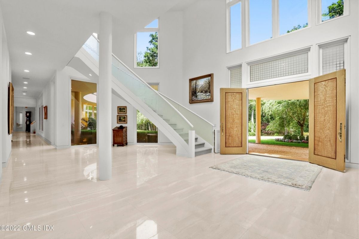 A foyer with a tiled floor, staircase, white walls, and a high ceiling.