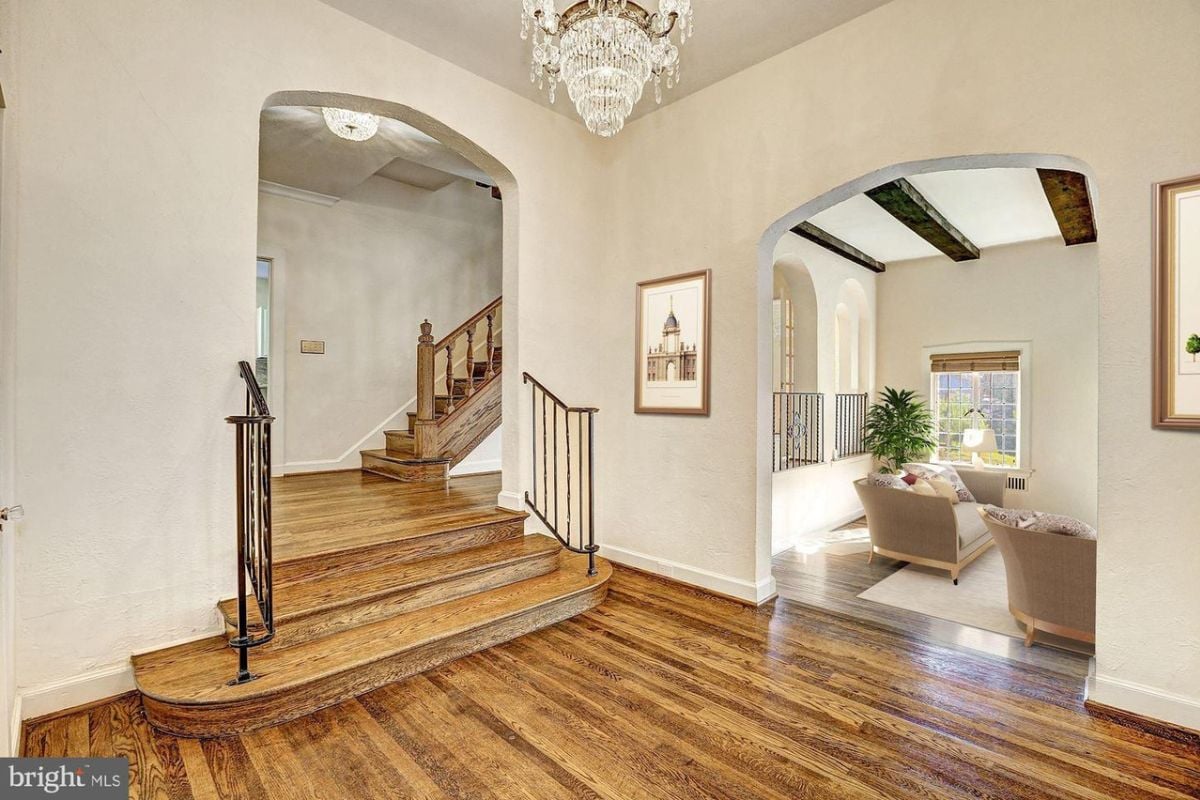 A foyer with a staircase, wooden floor, and chandelier.