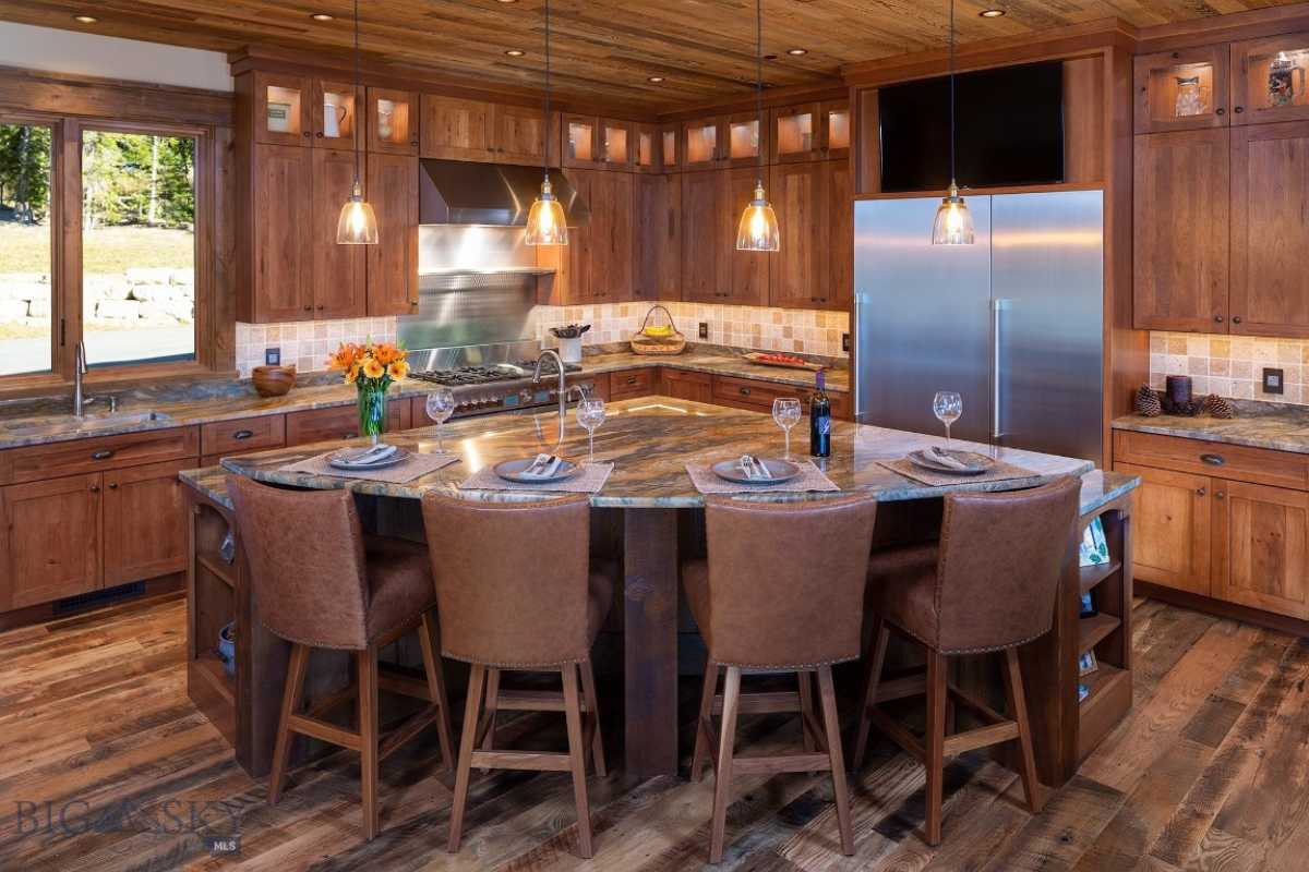 A dining room and kitchen with a table, chairs, wooden floor, wooden ceiling, countertop, sink, and kitchen appliances.