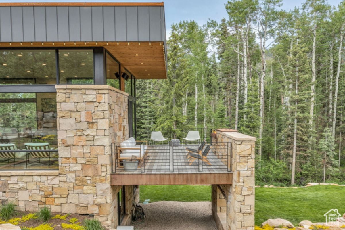 A wooden deck with chairs, a couch, and metal railings.