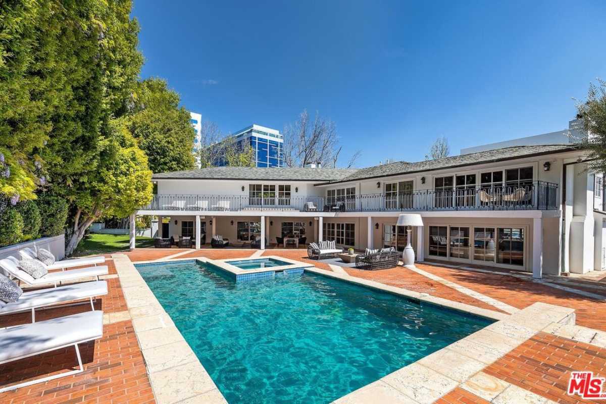 A swimming pool with a jacuzzi and chairs by the poolside.