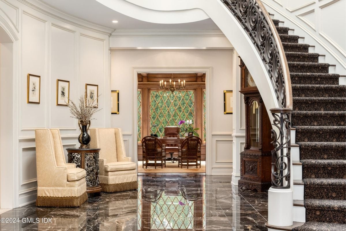 A foyer with chairs, a tiled floor, staircase, and white walls.
