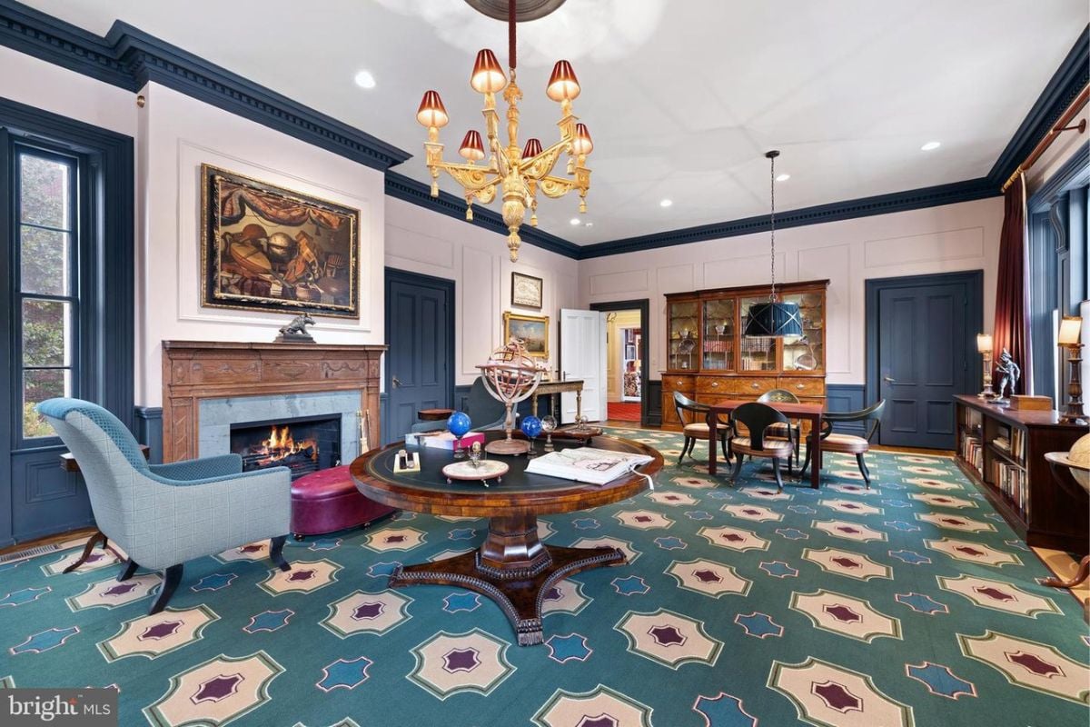 a living room with rug, fireplace, couches, chandelier, paintings, chairs and white ceiling