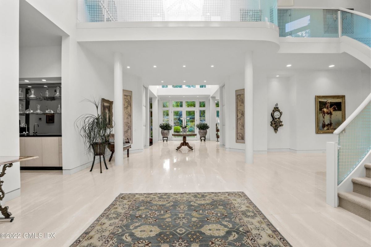 A foyer with a tiled floor, rug, and white walls.