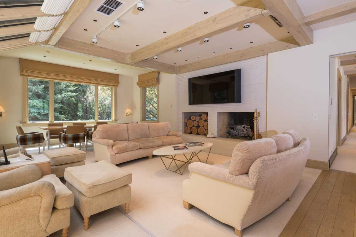 A living room with a rug, fireplace, TV, couches, center table, and beamed ceiling.