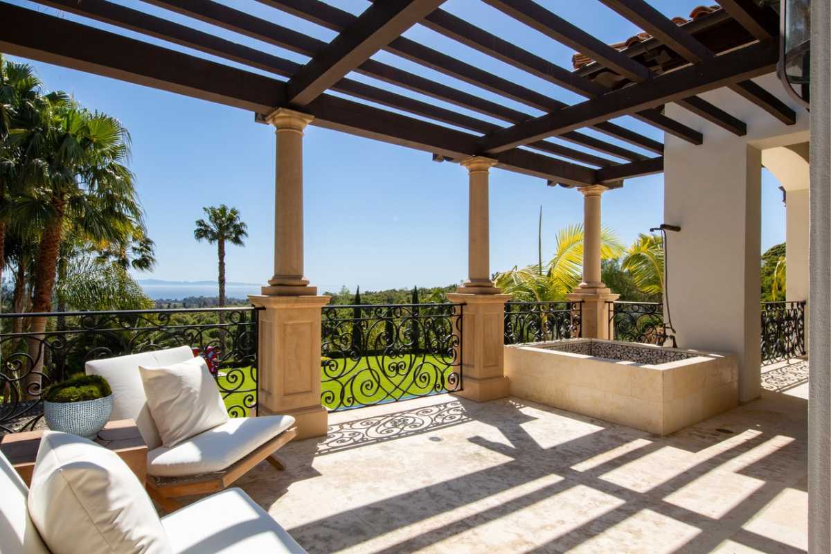 A patio with couches and a fence.
