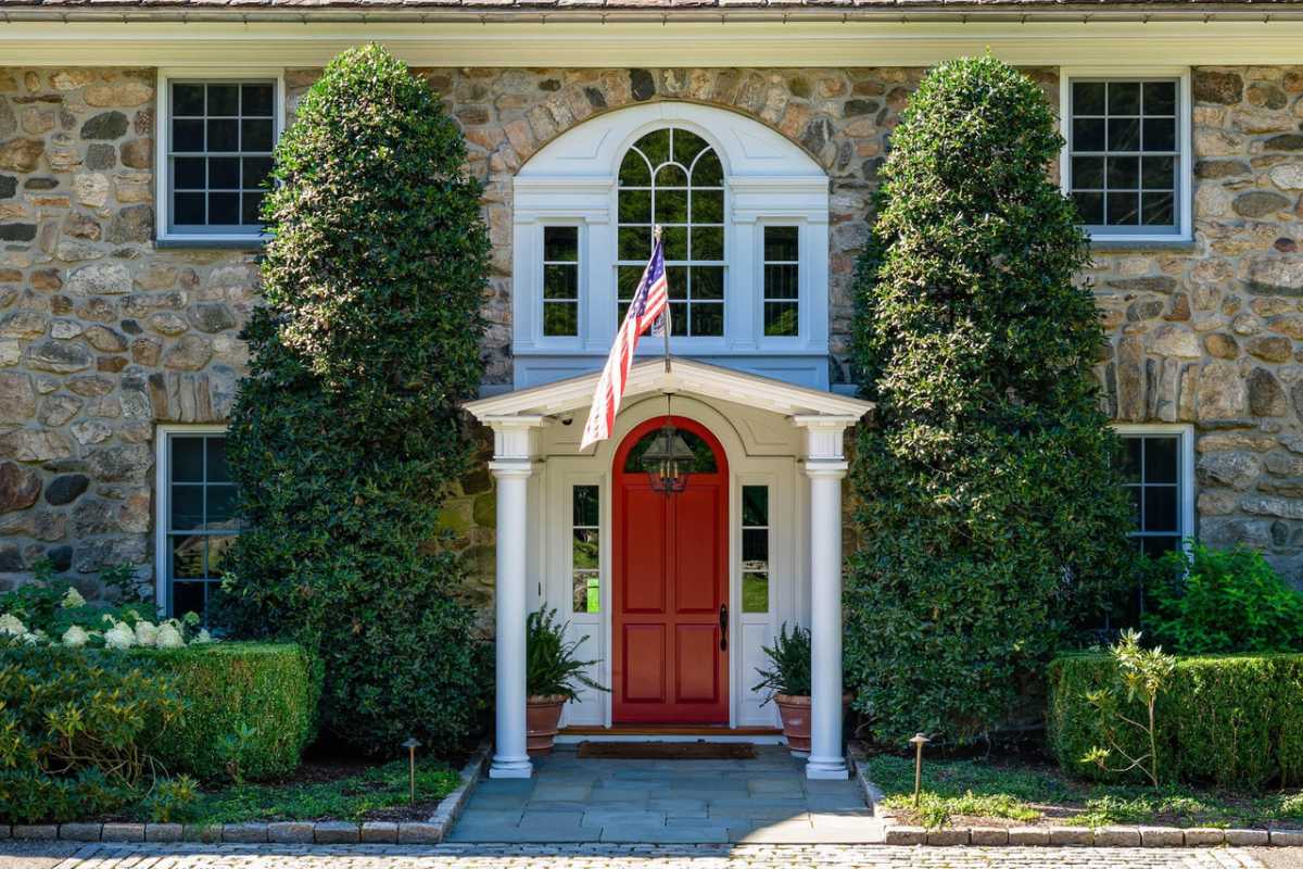 A front entry with a red door and flag.