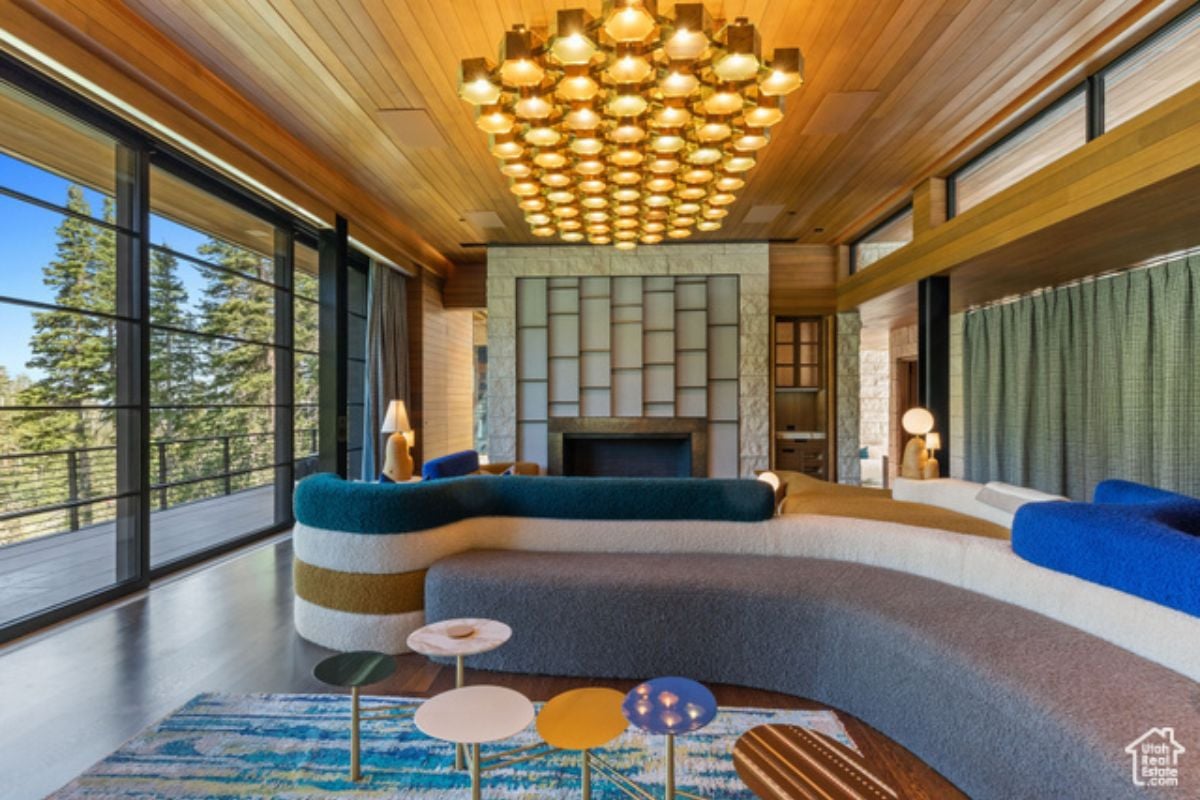 Living room with couches, wooden ceiling, fireplace, and windows.