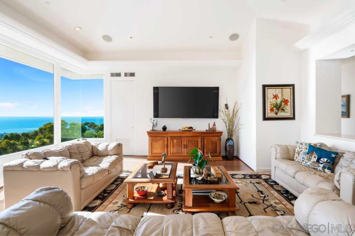 A living room with a rug, window, white ceiling, TV, coffee tables, and couches.