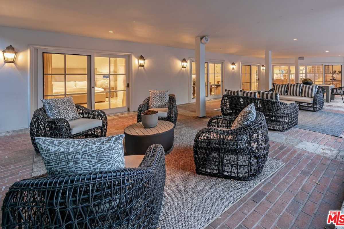 A porch with a brick floor, couches, chairs, and coffee tables.