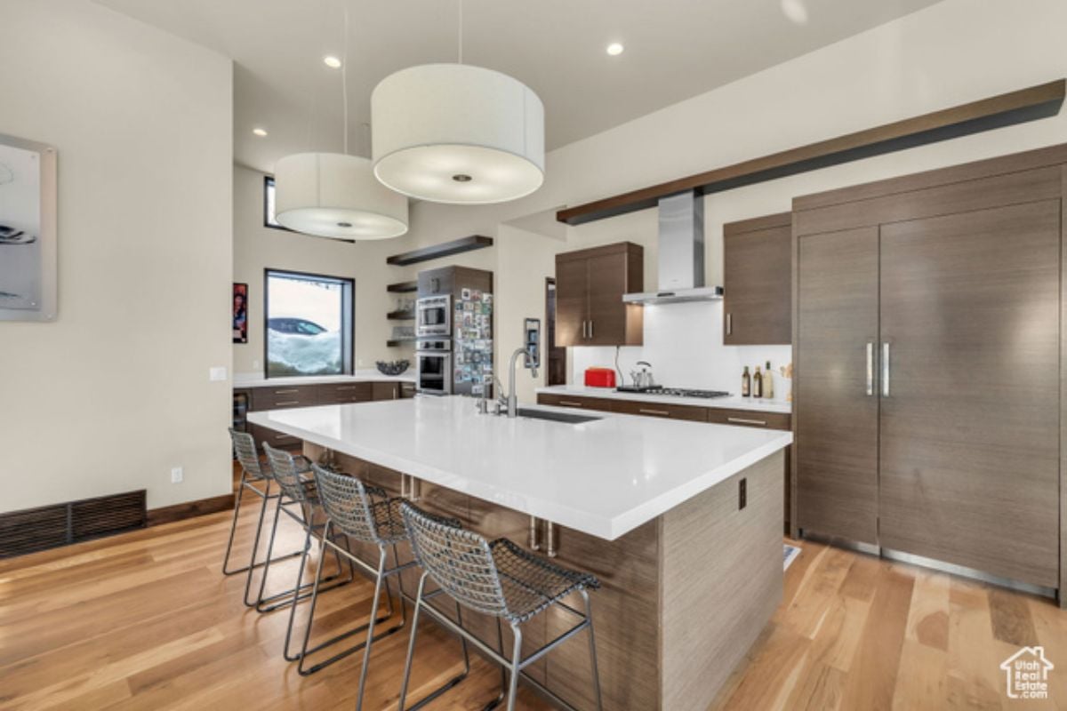 A kitchen with an island, chairs, cabinets, countertop, and sink.