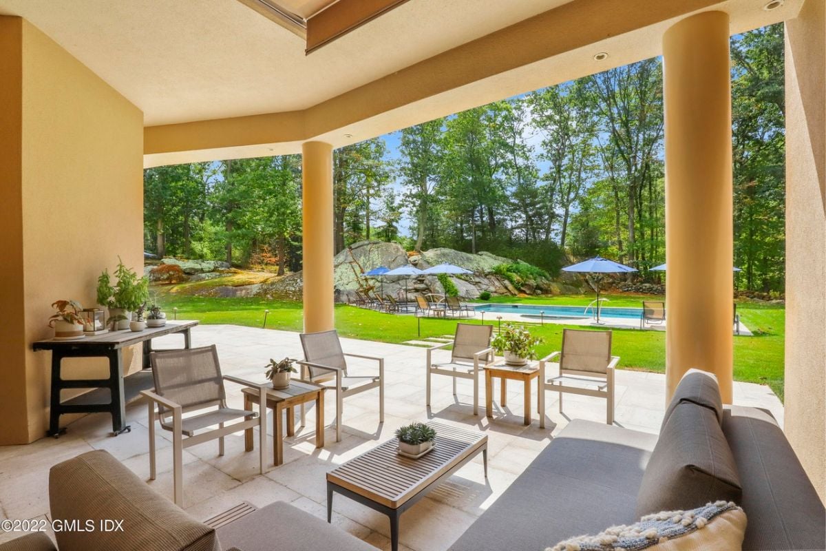 A covered patio featuring a couch, chairs, and a coffee table.