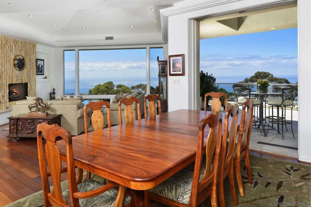 A dining room with a rug and a wooden dining table surrounded by chairs.