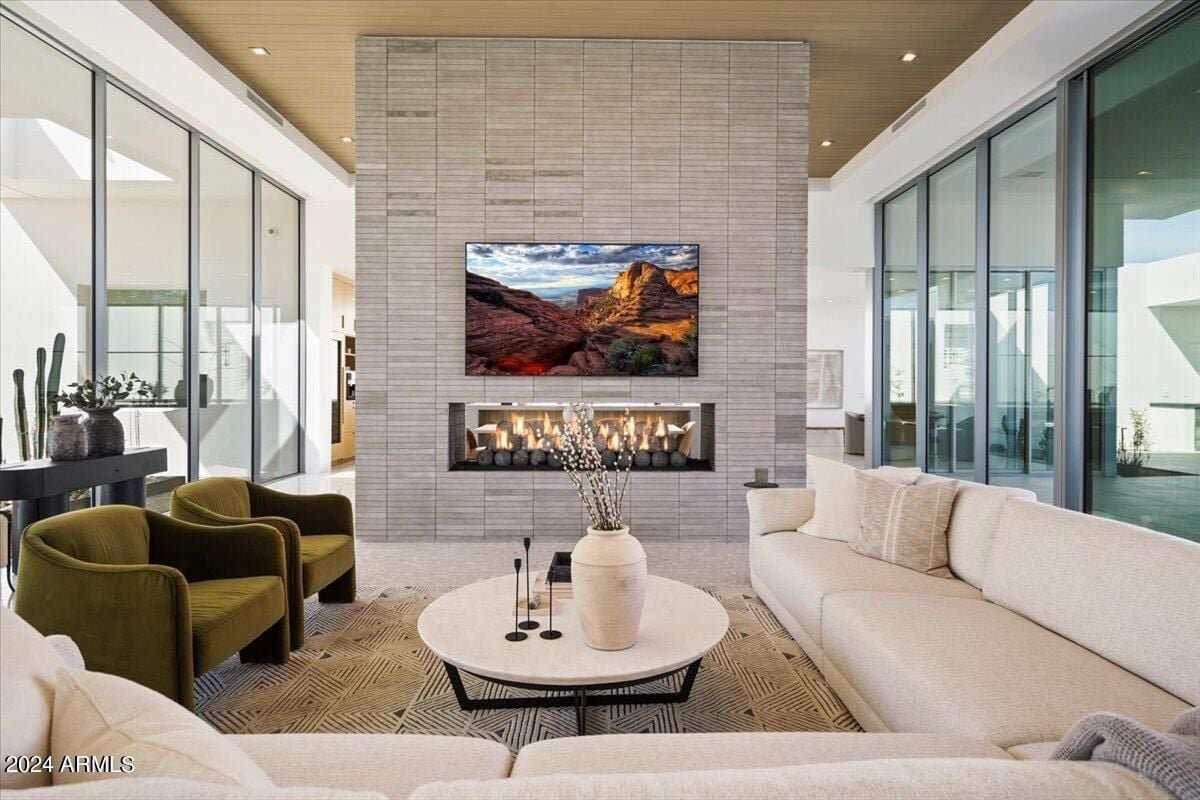 A living room with a couch, chairs, a center table, TV, and fireplace.