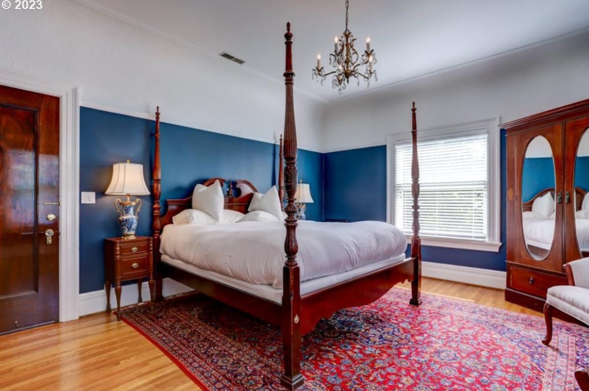 Bedroom with a chandelier, a large bed and a large rug.