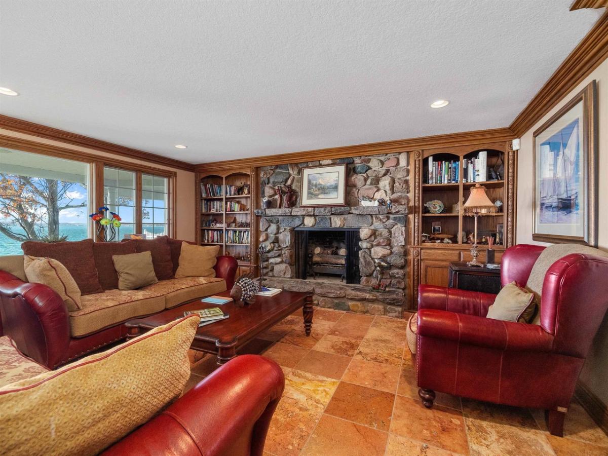 Living room with a couch, glass windows, fireplace and a wooden table.