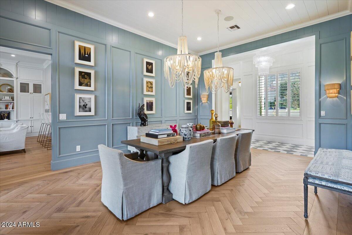 Dining room with chandeliers and wooden floor.