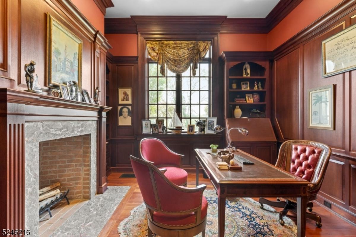Home office with a desk, chairs, glass windows and a large rug.