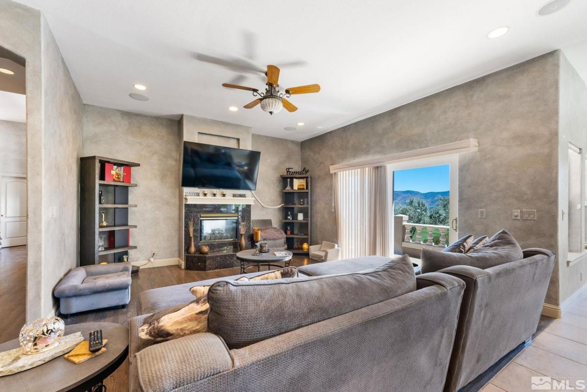 Living room with couches, TV, glass doors, fireplace and custom lights.