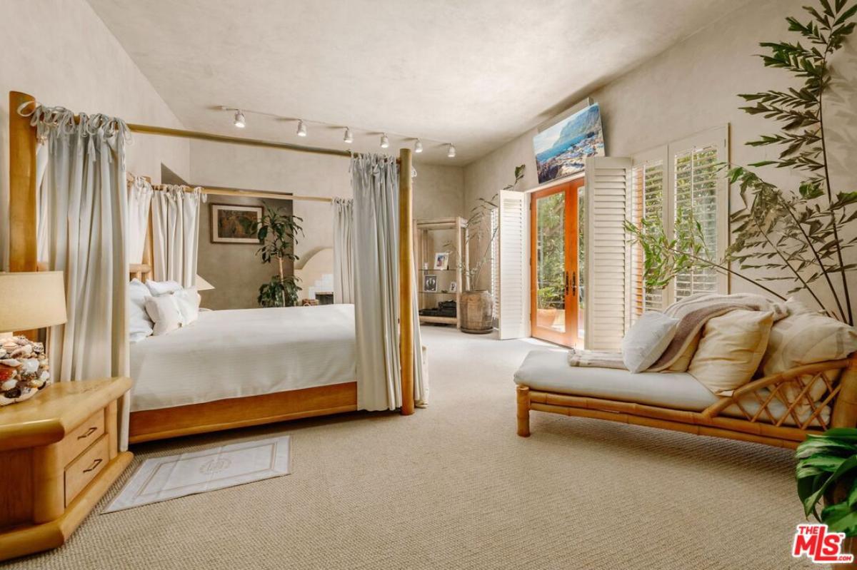 Bedroom with a large bed, custom lights, glass doors and a carpet flooring.
