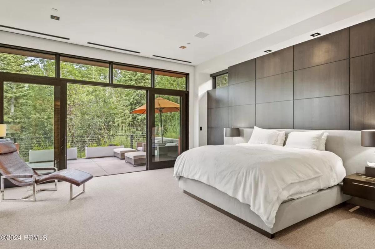 Bedroom with a large bed, carpet flooring and glass doors.
