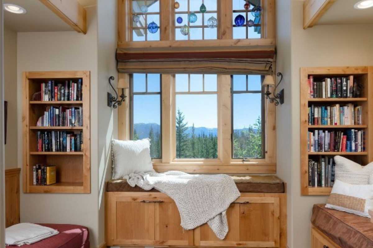 A reading nook with a window seat, shelves, windows, a couch, and cabinets.