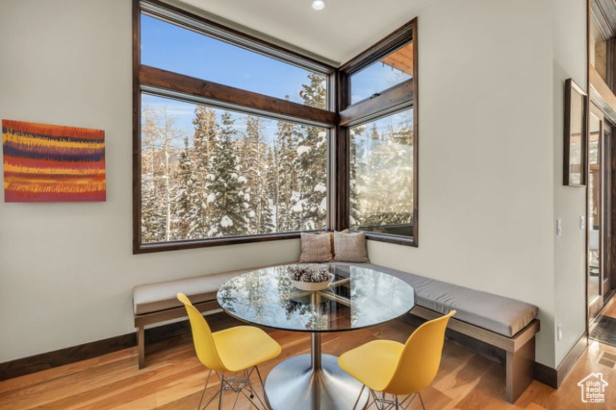 A breakfast nook with a small table, chairs, bench, and window.