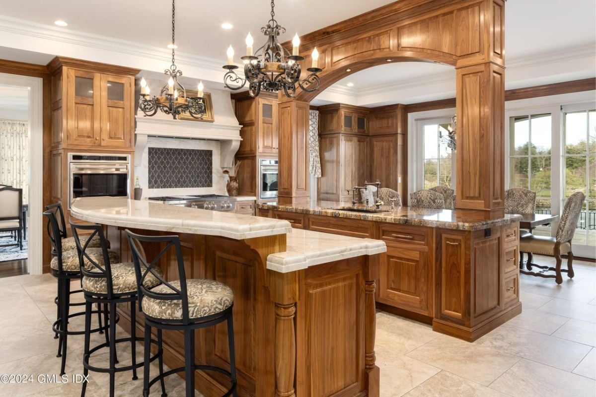 The kitchen, complete with a bar and chairs, features indoor elements such as cabinetry, countertop, furniture, home appliances, cupboards, and a kitchen island.